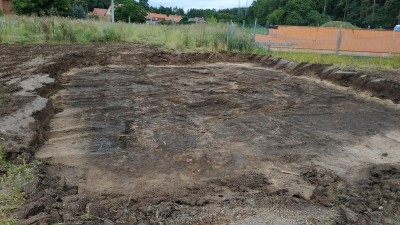 Na fotografii je vidět tmavě zbarvený zahloubený dům, tzv. polozemnice. Foto: Obec Holedeč